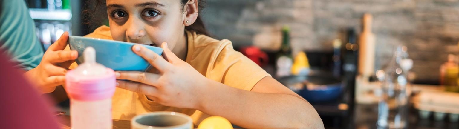 Niña tomando su comida en un comedor comunitario